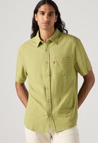 Camicetta a maniche corte, di colore verde chiaro, con bottoni, realizzata in tessuto testurizzato, dotata di taschino sul petto e con un discreto etichetta del logo Levi's.