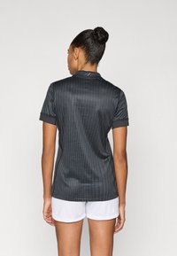 Must musta spordisärk vertikaalsete triipudega, lühikeste varrukate ja kraega; tagaküljel väikeste siniste ja punaste detailidega.