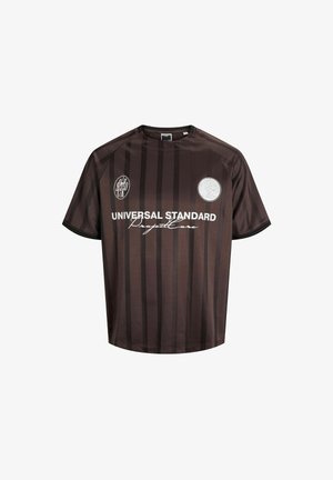 Brązowy trykot z krótkim rękawem w pionowe czarne paski. Posiada okrągły dekolt, naszywki z logo oraz nadrukowany tekst z przodu.