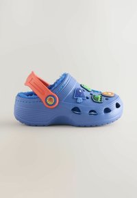Blue rubber clog with a fuzzy interior, featuring light blue accents, a bright orange strap, and multiple colorful decorative charms.