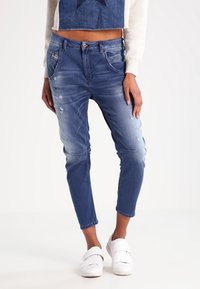 Jeans i medium blått med slitna detaljer och en tapered passform. Har en standard midja och femficksdesign.