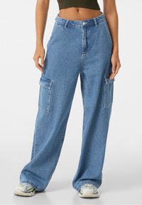 Ljusblå denim cargo-byxor med en avslappnad passform, utrustade med sidofickor och knäppning i midjan. Bekväm, vid byxddesign.