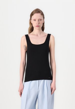 Zwarte geribbelde tanktop met een vierkante halslijn en brede schouderbanden, gecombineerd met lichtblauwe, loszittende broek. Opvallende stikdetails.
