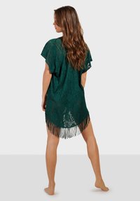 Kimono de encaje color verde azulado con mangas cortas, diseño floral intrincado y un dobladillo con flecos. Textura ligera y semitranslúcida para un estilo en capas.