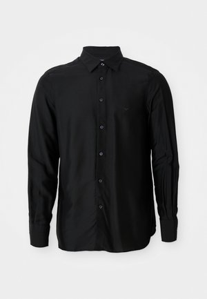 Svart langermet skjorte laget av glatt stoff, med krage som kan kneppes ned, frontknapper og en liten brodert logo.