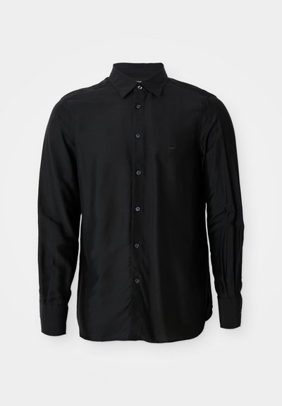 Svart långärmad skjorta i slät tyg, med knappkrage, framknappar och en liten broderad logga.