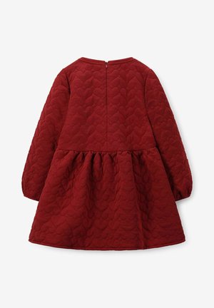 Robe matelassée rouge avec des manches longues, un col rond et une jupe évasée. Elle présente une texture en forme de cœur et une fermeture éclair dans le dos.