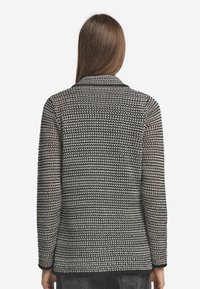 Svart och vit mönstrad vävd kavaj med spetskrage, långa ärmar och rak passform. Texturerad tyg med en mjuk känsla.