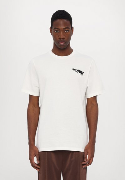 T-shirt en coton blanc à manches courtes, col rond, doté d'un graphisme noir imprimé sur le côté gauche. Texture lisse, coupe standard.