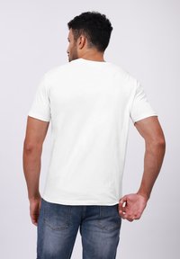 Hvid kortærmet t-shirt med rund halsudskæring. Stoffet ser glat og let ud, kombineret med mørk denim jeans.
