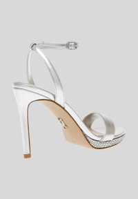 Sandale à talons hauts argentée avec une finition métallique, bride de cheville, bout ouvert et une plateforme ornée de strass le long du bord.