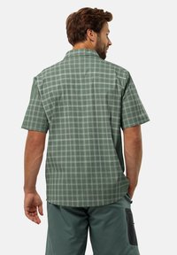 Korte mouwen shirt in lichtgroen met een wit geruit patroon, met een kraag en een relaxte pasvorm. Achteraan zijn de naden en de zoom zichtbaar.