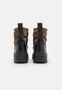 Bottines marron et noires avec un haut rembourré, des semelles en caoutchouc et des lacets tissés. Marquage sur les talons et finition texturée.