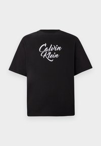 Camiseta negra de manga corta con el logotipo en cursiva "Calvin Klein" en blanco centrado en el pecho, presentada contra un fondo claro y liso.