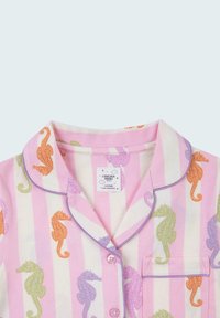 Pink and white striped pajama top featuring seahorse patterns in orange, green, and purple. Soft fabric with a collar and pocket detail.