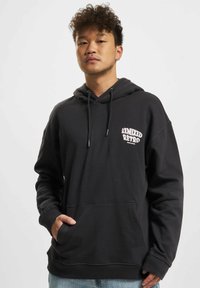 Black fleece hoodie with a front pocket, drawstring hood, and 'Remixed Retro' graphic in white on the left chest. Soft texture.