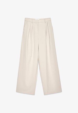 Béžové nohavice s širokými nohavicami a skladkami, s hladkým povrchom a pútkami na opasok. S prevládajúcim strihom, ktorý ponúka voľný strih okolo nôh.