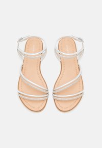 Silver strappy sandals med en slät beige innersula, dekorerade med små rhinestones längs remmarna, justerbar ankelspänne.
