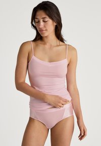 Camisola rosa chiaro con spalline sottili e scollatura dritta, abbinata a un perizoma senza cuciture dello stesso colore. Texture liscia, design minimale.