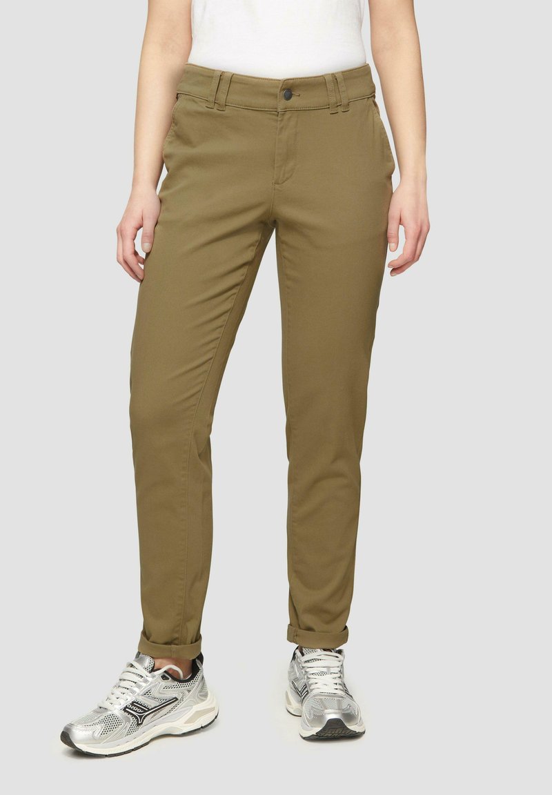 Olivgrüne Hose mit geradem Schnitt, aus weichem Stoff gefertigt. Verfügt über einen vorderen Knopfverschluss und seitliche Taschen, kombiniert mit silbernen Sportschuhen.