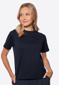T-shirt di cotone blu navy con collo tondo e maniche corte, caratterizzato da un logo ricamato discreto sul petto. Texture liscia.