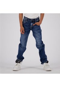 Blå denimjeans med avslappnad passform, fem fickor, blekta områden och en klassisk design. Bärs med vita hög-top sneakers.