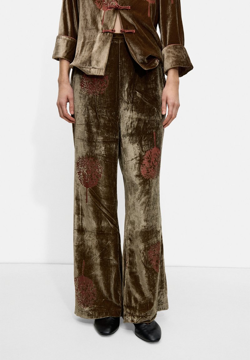 Zielony oliwkowy dwu-elementowy zestaw z weluru z szerokimi spodniami. Haftowane brązowe kwiatowe wzory na obu elementach, z zapięciem na guzik.