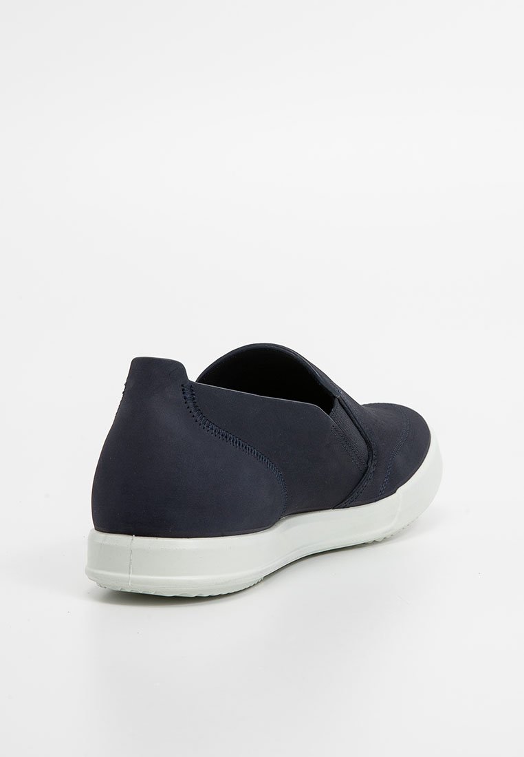 Granatowe sneakersy slip-on z białą podeszwą, widoczne przeszycia wzdłuż pięty i boków, sfotografowane z kąta tylno-prawa na białym tle.