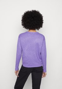 Fioletowy dzianinowy sweter z długimi rękawami i luźnym fasonem, charakteryzujący się subtelną teksturą i zaokrąglonym dekoltem. Minimalistyczny design, pokazany od tyłu.