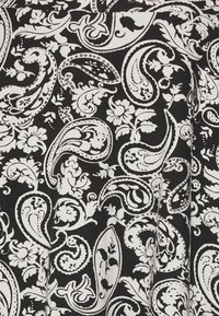 Tecido preto com um padrão detalhado em branco de paisley e flores, com espirais e designs intrincados por todo o material.