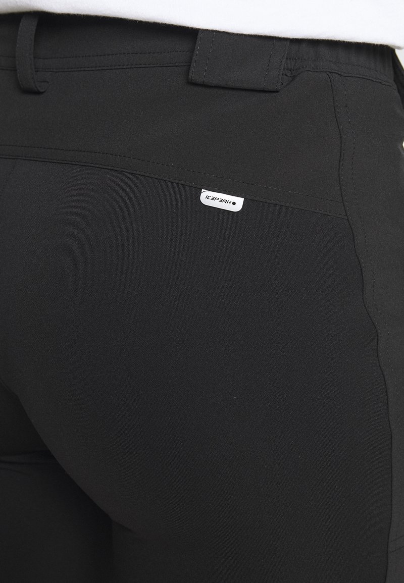 Pantaloni neri realizzati in tessuto elastico, con un design elegante, una texture liscia e una piccola etichetta bianca con il marchio vicino alla tasca posteriore.