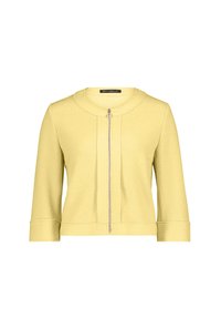 Žlutá bunda na zip s kulatým výstřihem a tříčtvrtečními rukávy, s texturovanou tkaninou a výrazným zipem vpředu.