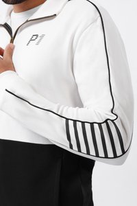 Witte en zwarte ritssporttrui met een hoge kraag, gestructureerde schouders en gestreepte accenten op de mouwen. Zachte textuur, atletische pasvorm.