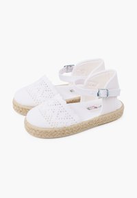Weiße Espadrille-Sandalen mit Schnürdetails, einer gewebten Jutesohle, verstellbarem Knöchelriemen und weichem Stoffoberteil. Einfaches, offenes Design.