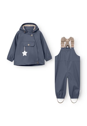 Veste de pluie imperméable bleu foncé pour enfants avec capuche et réflecteur étoile sur le devant, assortie à une salopette imperméable avec bretelles beige réglables.