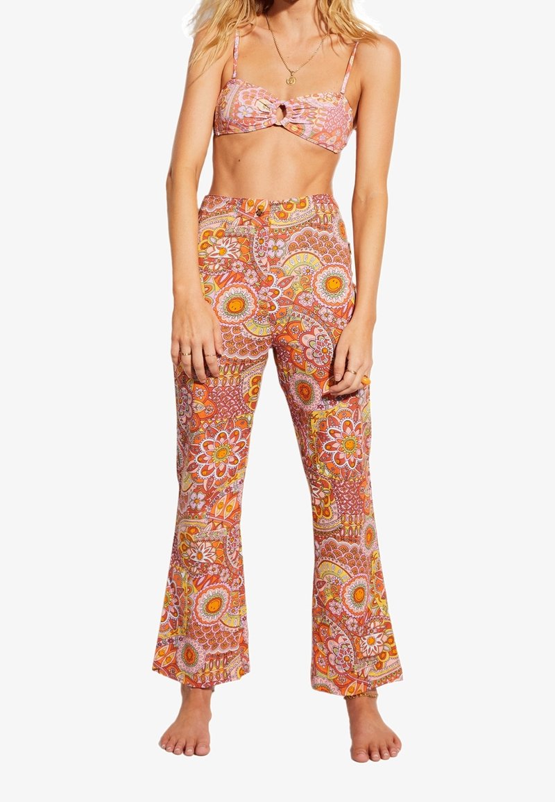 Ensemble deux pièces à motif floral comprenant un crop top noué et un pantalon évasé dans des teintes vives de rose, orange et jaune. Matière en coton.