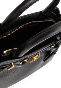 Crna kožna torbica s teksturiranom površinom, zlatnim metalnim dijelovima, zatvaranjem na vrhu s patentnim zatvaračem i dvostrukim ručkama. Pogled iznutra prikazuje džep sa patentnim zatvaračem i pregrade.