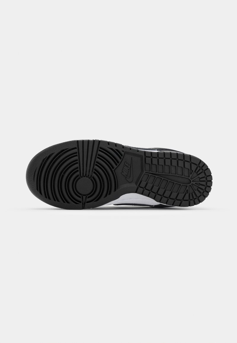 Nike-Sneaker-Sohle aus schwarzem Gummi, mit strukturiertem Muster und kreisförmigen Akzenten. Weiße Zwischensohle an den Seiten sichtbar.