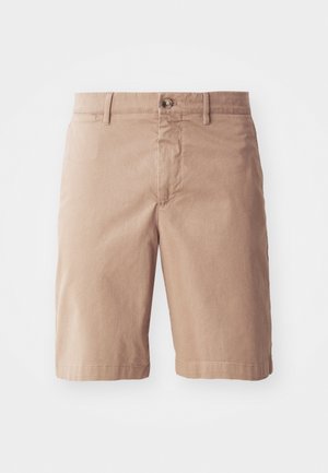 Shorts en coton beige avec une coupe droite, présentant une fermeture à bouton à l'avant et des passants de ceinture. Texture lisse avec des détails de couture minimalistes.