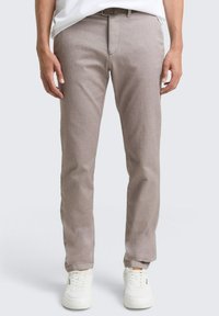Lichtbruine, slim-fit broek van gestructureerde stof, met een platte voorkant, riemlussen en een ritssluiting. Gecombineerd met witte sneakers.