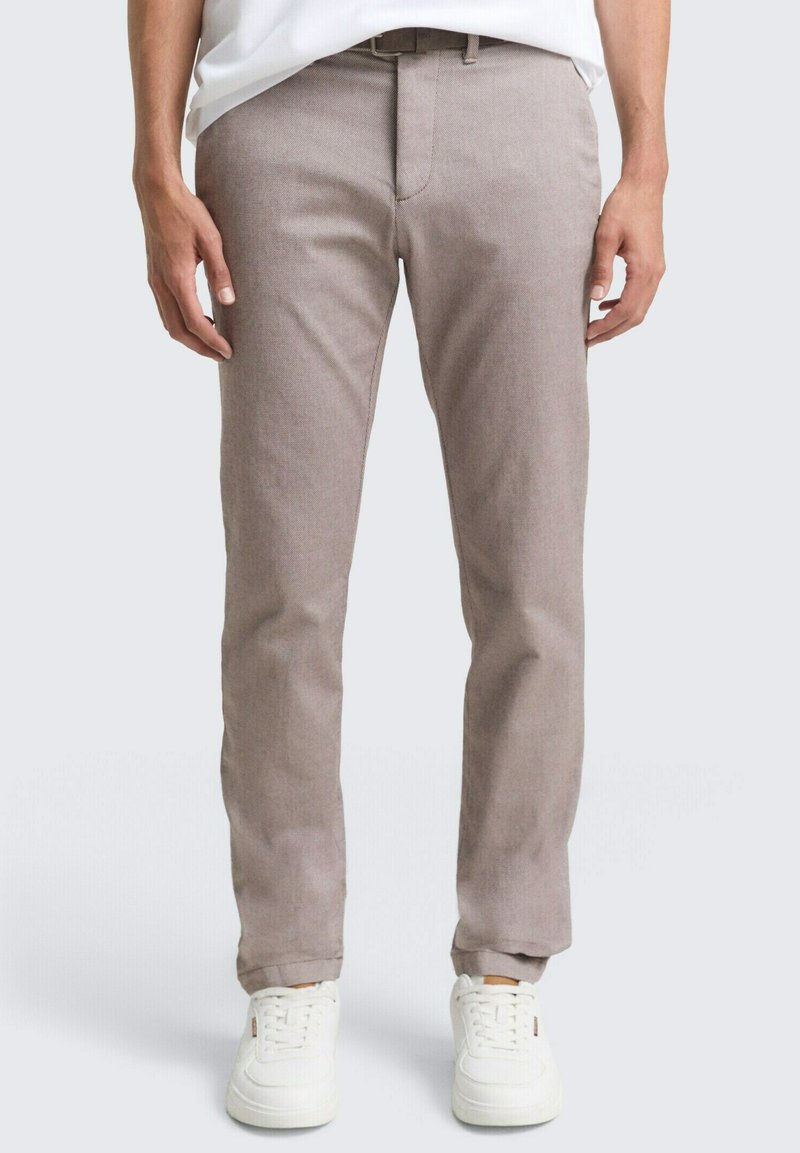 Lichtbruine, slim-fit broek van gestructureerde stof, met een platte voorkant, riemlussen en een ritssluiting. Gecombineerd met witte sneakers.