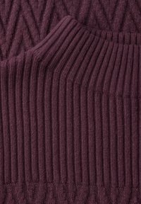 Maglione lavorato a maglia di colore viola intenso, caratterizzato da una combinazione di motivi a zigzag rialzati e a coste, che evidenziano la texture e gli elementi di design intricati.
