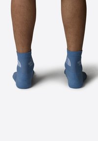 Calcetines azul claro de longitud hasta el crew, hechos de material suave y elástico. Presentan puños acanalados y detalles del logo en blanco a los lados.