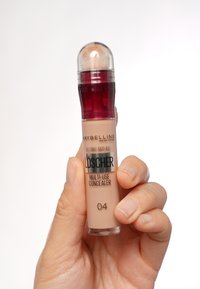 Maybelline Mehrzweck-Concealer in einer klaren Tube mit einem runden Pinselspitze, einer Mischung aus Beige- und Hellrosa-Tönen, mit einem roten Akzentdeckel.