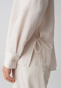 Licht gestreepte langemouwen shirt met een knoop in de taille, gemaakt van zachte stof, met knoopmanchetten en een relaxte pasvorm. Kleur: lichtroze en wit.