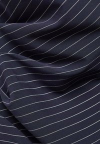 Tissu bleu marine foncé avec de fines rayures blanches régulièrement espacées, légèrement froissé et drapé.