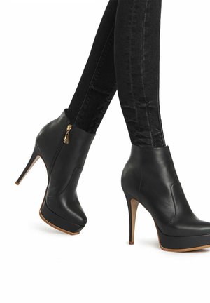 Schwarze Leder-Stiefeletten mit Stiletto-Absätzen, ausgestattet mit einem Reißverschluss vorne und einer Plateausohle. Das Design ist schlank mit einer glatten Textur.