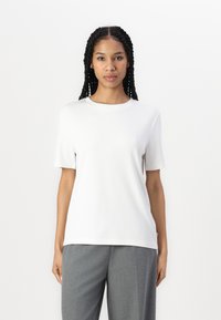 Vit kortärmad t-shirt i mjukt, lätt tyg med rund halsringning. Matcher grå högmidjade byxor.