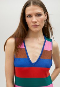 Koftklänning i kroppsnära modell med djup V-ringning, flerfärgade horisontella ränder i blått, rosa, grönt, rött och brunt, med en glänsande yta.