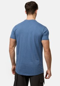 Blå bomulds-T-shirt med korte ærmer, rund halsudskæring og lige skæring i kanten. Glat tekstur, minimale sømme, ingen synlige logoer.